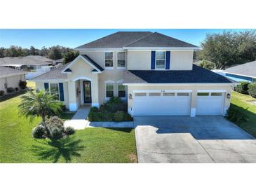 Two-story house with a three-car garage, landscaping, and a large driveway at 206 Clovis Pass, Winter Haven, FL 33880