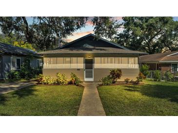 Tan Bungalow style home with a walkway, landscaping, and a well-maintained lawn at 1127 N Stella Ave, Lakeland, FL 33805
