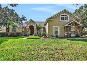 Tan two-story house with stone accents and manicured lawn at 109 Costa Loop, Auburndale, FL 33823