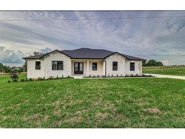 Stunning ranch home with white and stone exterior, a covered entry, and manicured lawn at 1001 Cody Bluffs Rd, Babson Park, FL 33827