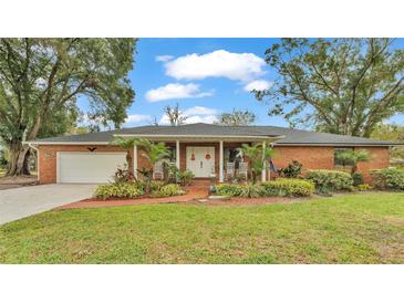 Brick ranch house with a covered porch, well-maintained landscaping, and a two-car garage at 4264 Stafford Dr, Winter Haven, FL 33880