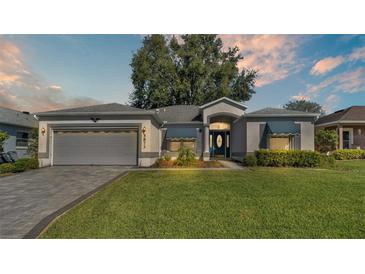 One-story home with gray exterior, attached garage, and landscaped lawn at 5873 Macaw Pl, Lakeland, FL 33809