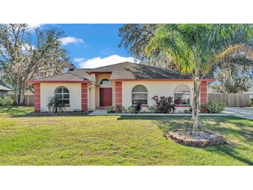 Single-story home with red accents and a lush green lawn at 1555 Archers Path, Lakeland, FL 33809