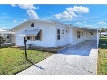 White single-wide manufactured home with covered carport and paved driveway at 6683 Briarhill Ne Dr, Winter Haven, FL 33881