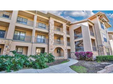 Inviting condo building with stone accents and lush landscaping at 904 Charo Pkwy # 517, Davenport, FL 33897