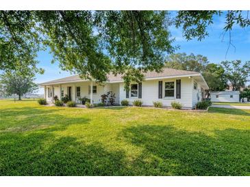 Single story home with white siding, large yard, and mature trees at 1730 Broken Arrow N Trl, Lakeland, FL 33813