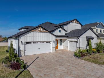 Two-story home with white siding, stone accents, and a three-car garage at 2728 Sunrise Landing Ln, Lakeland, FL 33812