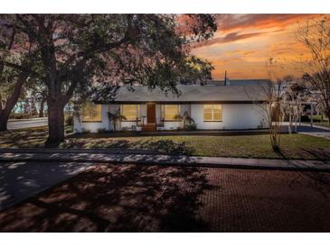 Charming bungalow with a white exterior, manicured lawn, and brick driveway at 425 E Belmar St, Lakeland, FL 33803
