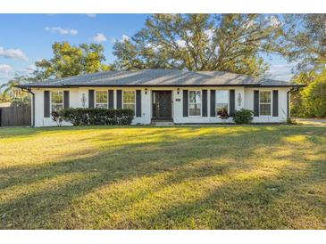 White brick ranch house with gray shutters, landscaping, and a large yard at 4409 Hallam Hill Ln, Lakeland, FL 33813
