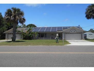 House exterior with solar panels, double garage, and palm trees at 806 South St, New Smyrna Beach, Fl 32168, FL 32168
