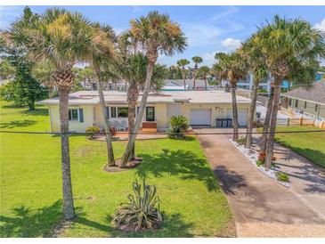 Aerial view of beach house with palm trees and driveway at 327 Due East St, New Smyrna Beach, FL 32169