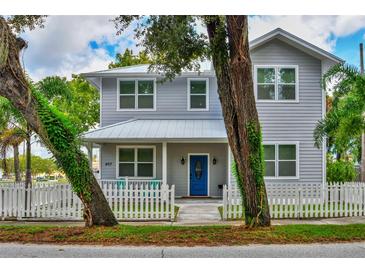 Two-story home with gray siding, white picket fence, and a blue front door at 407 Douglas St, New Smyrna Beach, FL 32168