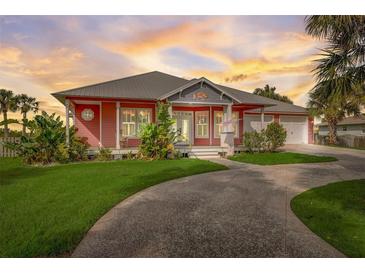 Charming coral house with metal roof, landscaping, and circular driveway at 300 Quay Assisi Ct, New Smyrna Beach, FL 32169