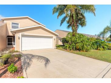 Tan townhome with white garage door and palm trees at 2266 Hawks Cove Cir, New Smyrna Beach, FL 32168