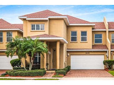 Tan two-story townhome with red tile roof, two-car garage, and palm trees at 3608 Romea Cir, New Smyrna Beach, FL 32168