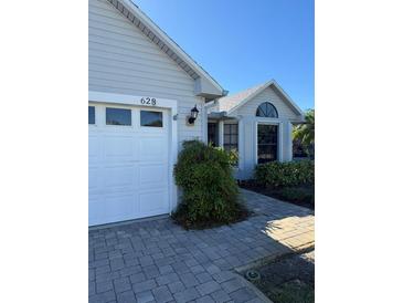 House exterior featuring a white garage door and landscaped walkway at 628 Middlebury Loop, New Smyrna Beach, FL 32168