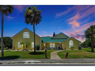 Charming yellow house with green roof, walkway, and lush landscaping at 886 Matthews Ave, New Smyrna Beach, FL 32169
