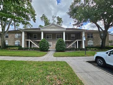 Two-story building exterior with manicured lawn and parking at 112 Reserve Cir # 104, Oviedo, FL 32765
