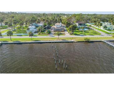 Aerial view of waterfront home with private dock, circular driveway, and lush landscaping at 4946 Halifax Dr, Port Orange, FL 32127