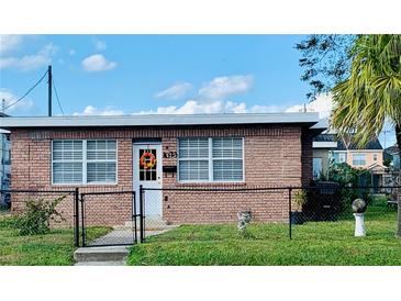 Brick home with a well-maintained lawn and a fenced yard at 1023 W Gore W St, Orlando, FL 32805