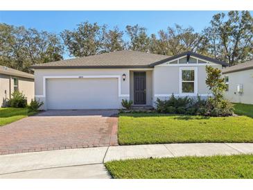 One story home with gray siding, brick paver driveway and landscaping at 28078 Poppy Ct, Leesburg, FL 34748