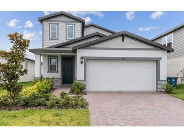 Two-story house with gray siding, two-car garage, and landscaping at 5953 Catamaran Ave, Haines City, FL 33844