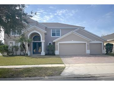 Two-story house with a three-car garage and landscaped lawn at 2887 Sweetspire Cir, Kissimmee, FL 34746