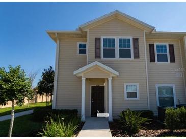 Two-story townhome with light beige exterior and dark brown door at 8947 Shine Dr, Kissimmee, FL 34747