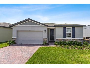 Single-Gathering home with gray siding, a two-car garage, and a landscaped lawn at 3606 Walking Stick Way, Poinciana, FL 34759