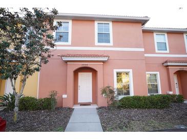 Two-story townhome with peach-colored exterior, landscaping, and walkway at 3004 Red Ginger Rd, Kissimmee, FL 34747