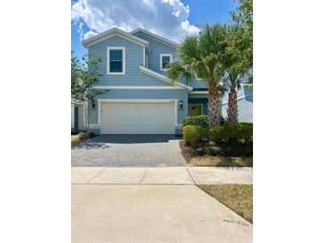 Two-story light blue house with gray paver driveway at 2442 Tangier Dr, Kissimmee, FL 34747