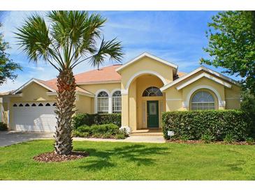 Charming yellow house with a lush green lawn and palm trees at 3327 Shrike Hill Court, Clermont, FL 34714