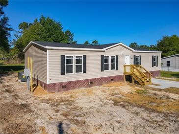 Tan exterior with black shutters, brick base, and wooden steps at 40407 Sunset Dr, Eustis, FL 32736