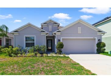 Single-story home with two-car garage and landscaped yard at 875 Fillmore Ct, Davenport, FL 33837