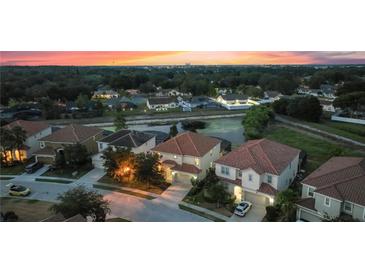 Aerial view of homes at dusk near a pond at 5204 Oakbourne Ave, Davenport, FL 33837