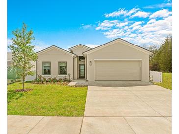 Tan house with two-car garage, landscaping, and driveway at 6368 Chorus Dr, Mascotte, FL 34753