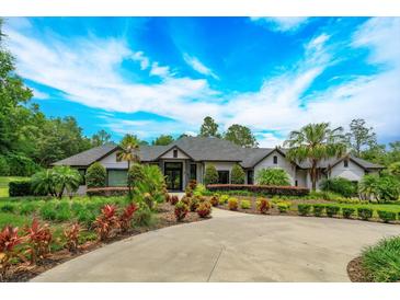 Luxury home with circular driveway and lush landscaping at 35635 High Pines Dr, Eustis, FL 32736