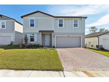 Two-story house with gray siding, light blue shutters, and a brick driveway at 28046 Poppy Ct, Leesburg, FL 34748