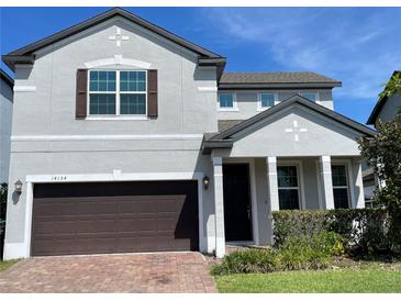 Two-story house with gray siding, brown garage door, and landscaping at 14154 Dove Hollow Dr, Orlando, FL 32824