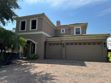 Two-story house with beige exterior, three-car garage, and a paver driveway at 2211 Rickover Pl, Winter Garden, FL 34787
