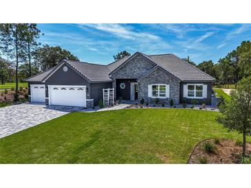 Single-Gathering home with stone and gray siding, three car garage at 17694 Sw 61St Lane Rd, Dunnellon, FL 34432