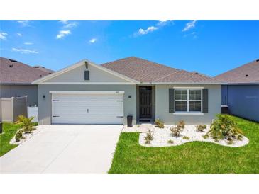 Charming one-story home with gray exterior, white garage door, and landscaping at 1157 Torrente Ln, Haines City, FL 33844
