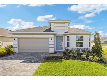 Modern one-story home with a light gray exterior and a taupe garage door at 3039 Suraj Cir, Tavares, FL 32778