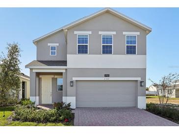 Two-story house with gray siding, two-car garage, and landscaping at 27512 Stellar Sea Way, Howey In The Hills, FL 34737