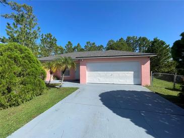 Pink house with a white garage door and a paved driveway at 821 Savona Pl, Kissimmee, FL 34758