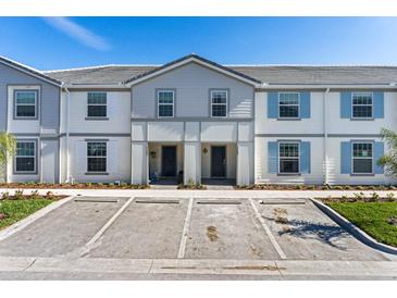 Two-story townhome with light grey siding and blue shutters at 7143 Oakmoss Loop, Davenport, FL 33837