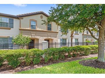 Townhouse exterior with a well-maintained lawn and iron fence at 2015 Majorca Drive, Kissimmee, FL 34747