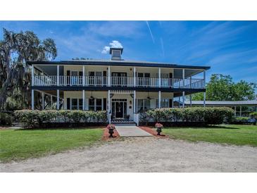 Two-story house with wrap-around porch and manicured lawn at 16600 Cleveland Ln, Umatilla, FL 32784