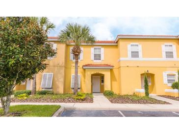 Two-story yellow townhome with a palm tree and walkway at 3004 White Orchid Rd, Kissimmee, FL 34747