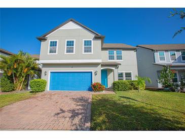 Two-story home with gray siding, blue garage door, and landscaped yard at 14166 Dove Hollow Dr, Orlando, FL 32824
